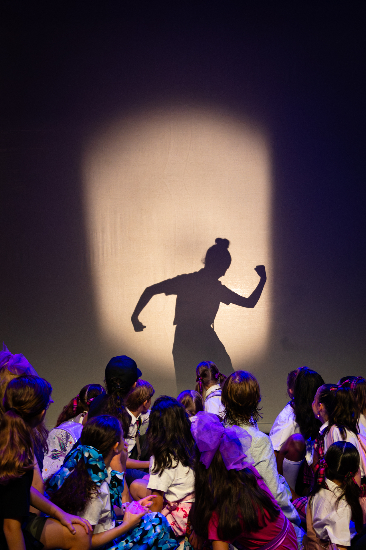 Silhouet van een danseres in de spotlight, bewonderd door kinderen in het publiek